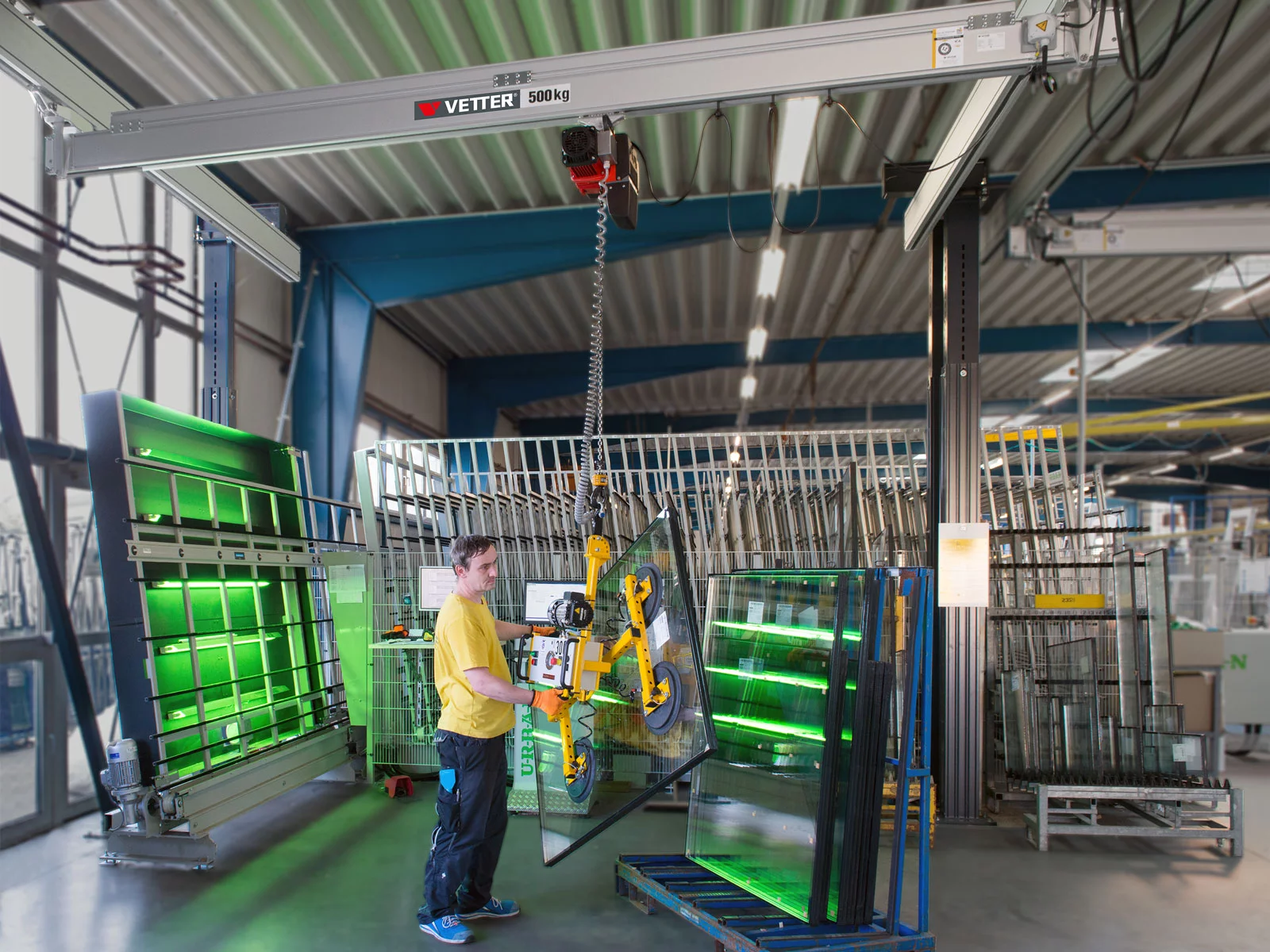 Nahaufnahme des ZSP-ErgoLine Leichtlportalkrans im Fensterbau. Ein Mitarbeiter hebt mit einem Vakuumheber Glasscheiben an.