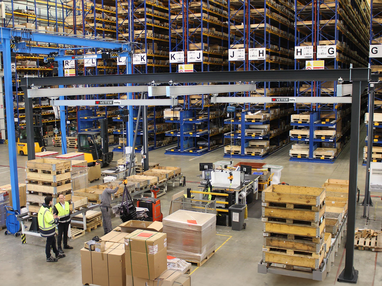 ZSP-ErgoLine Leichtkransystem in einer Logistikhalle. Ein Mitarbeiter hebt Waren von einer Palette.