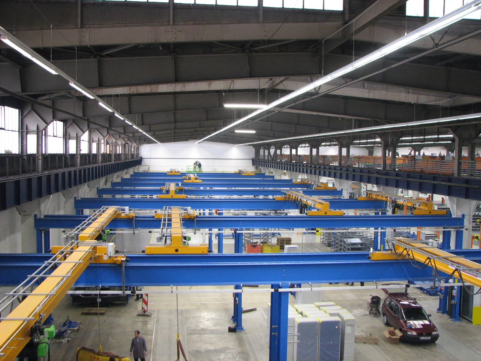 Blauer ZSP-Olympia Portalkran mit gelber Kranbrücke, aufgenommen von oben, im Einsatz in einer Fertigungshalle des Fahrzeugbaus.